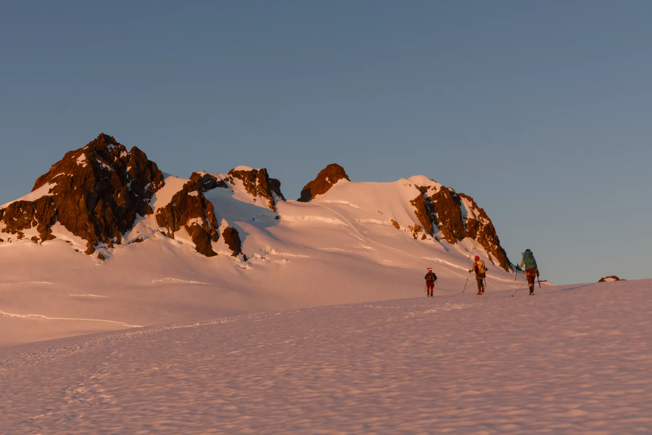 Three mountaineers climb toward Mount Olympus